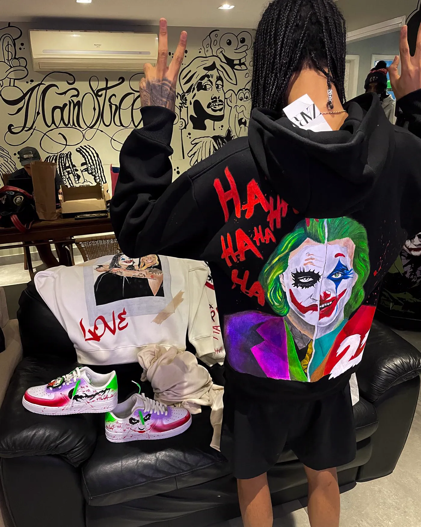 Casaco preto com o rosto do Coringa pintado à mão e HA HA HA em vermelho, ao lado do par de Air Force 1 do mesmo conjunto