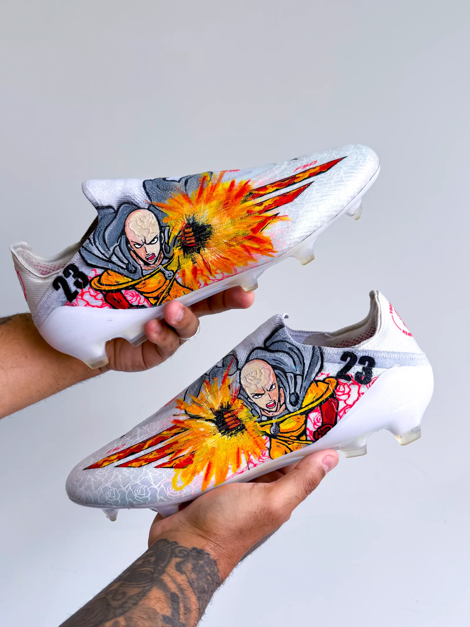 Chuteira branca pintada com o Saitama de One Punch Man e uma explosão laranja