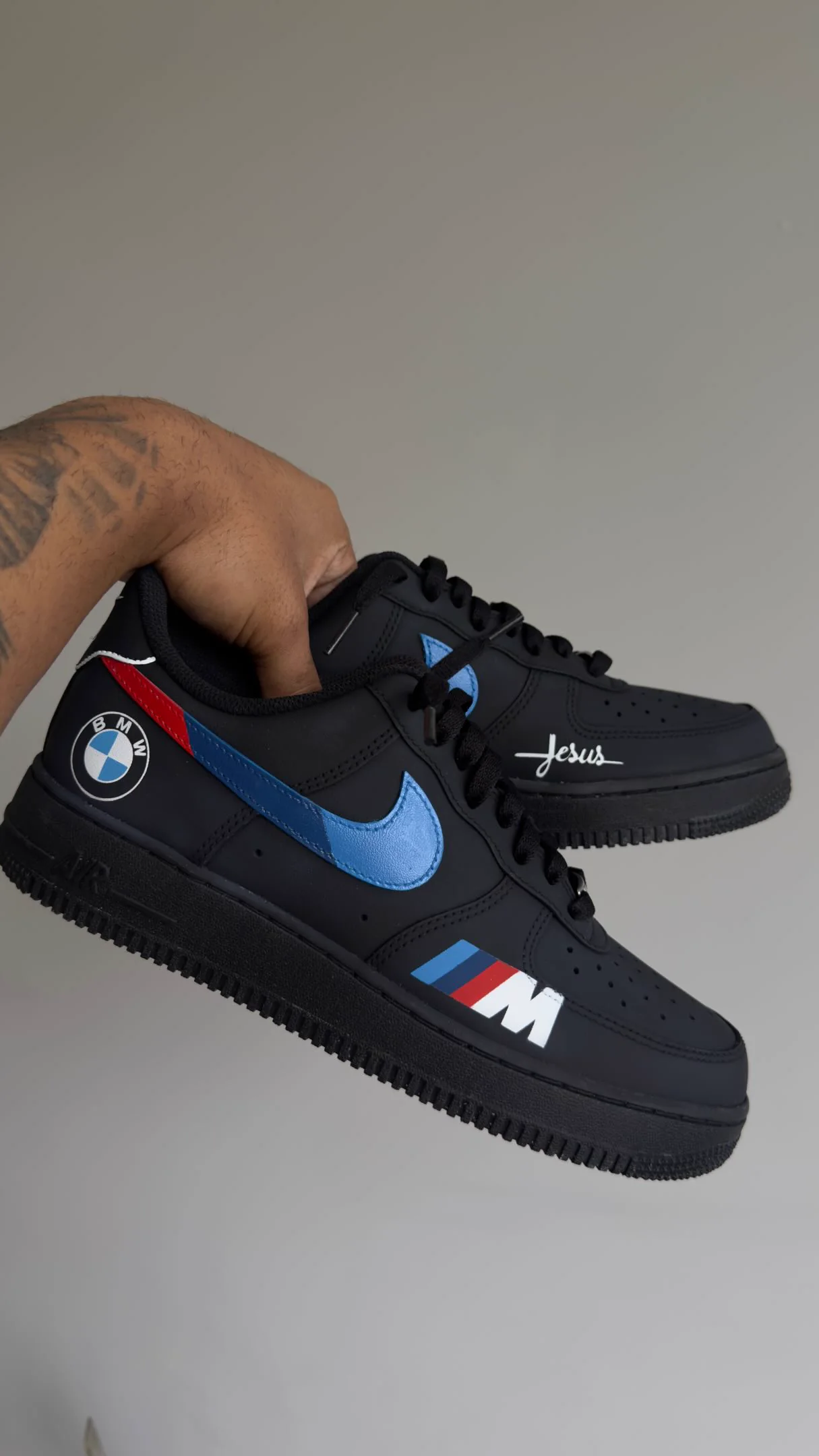 Par de Air Force 1 preto com o emblema da BMW, o swoosh azul e as faixas M